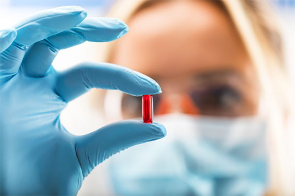 Young scientist holding a red transparent pill