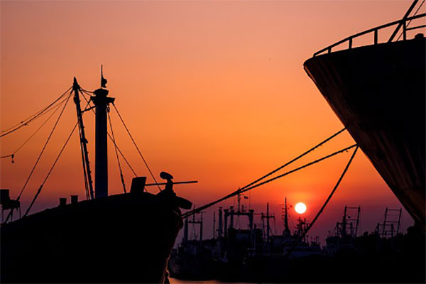Silhouette many ships moored along the coast against colorful sunset sky