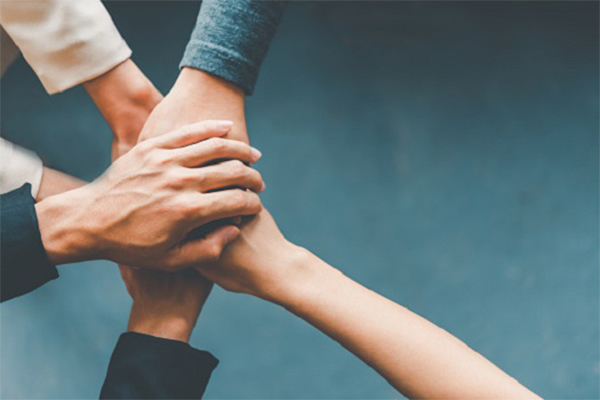 Top view hands of business people come together in a stack of hands to symbolize collaboration, teamwork to achieve goals and success. Pursuit of AI that Can be Trusted Getting More Attention in Pandemic Era 1