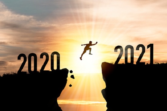Welcome merry Christmas and happy new year in 2021,Silhouette Man jumping from 2020 cliff to 2021 cliff with cloud sky and sunlight.